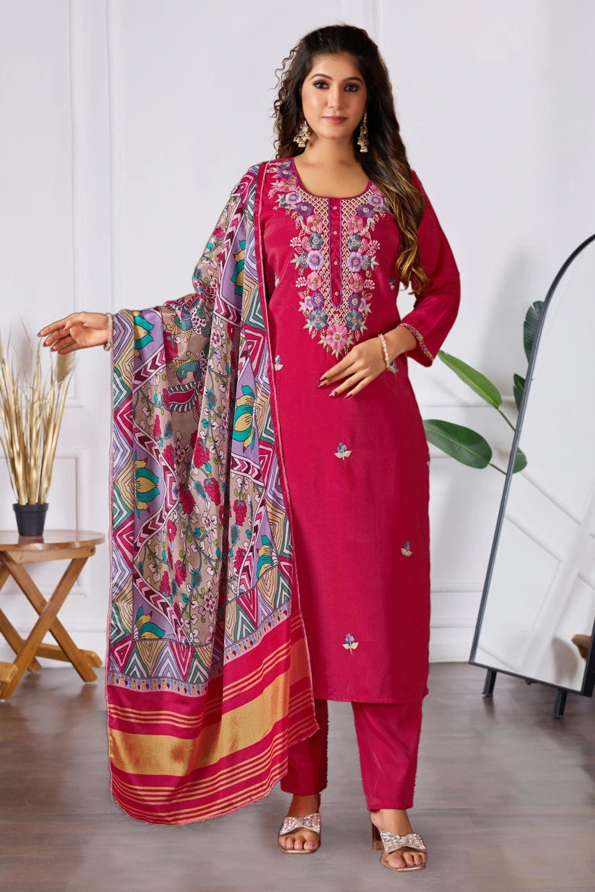 Woman wearing a pink embroidered outfit with a colorful scarf indoors.