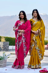 Two women in colorful sarees standing outdoors with a scenic background.