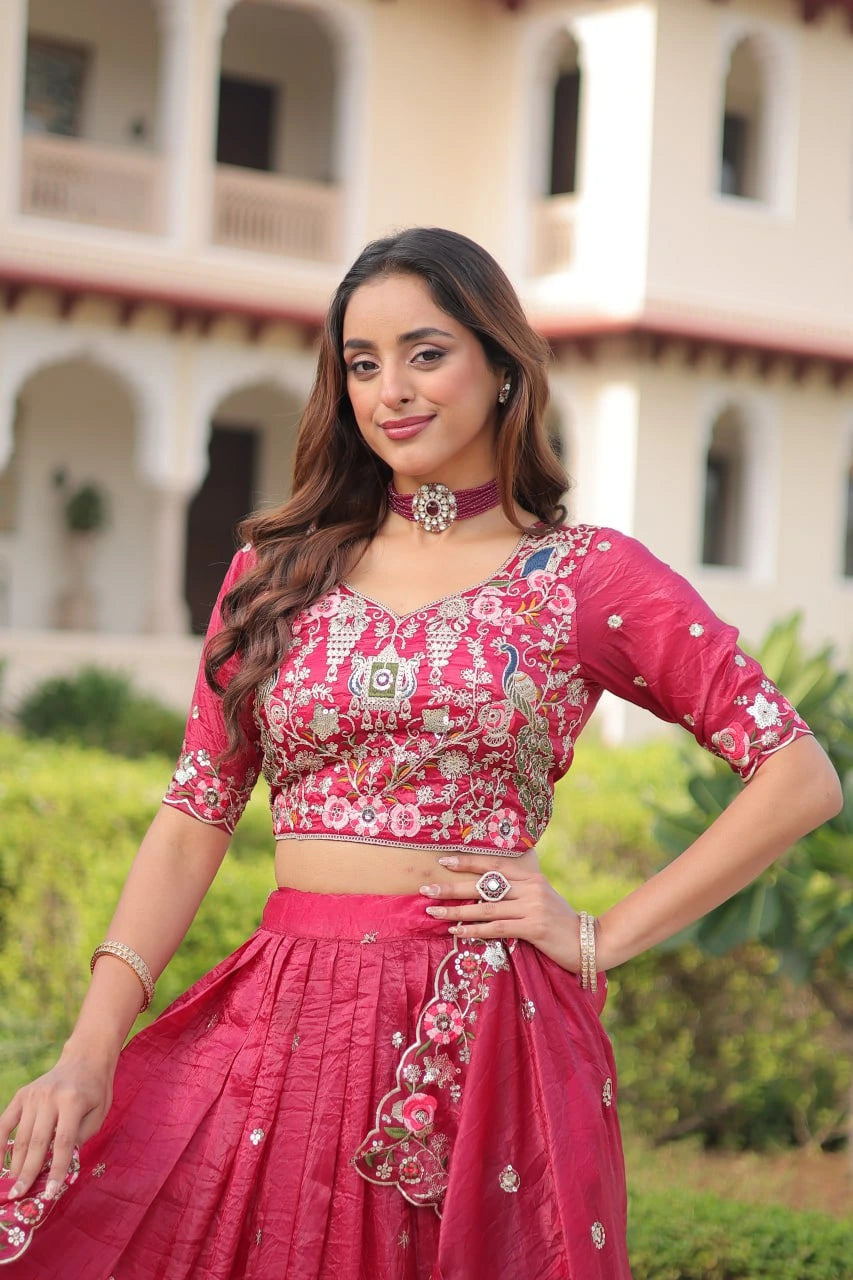 Woman in a pink traditional outfit standing outdoors with a building in the background