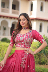 Woman in a pink traditional outfit standing outdoors with a building in the background