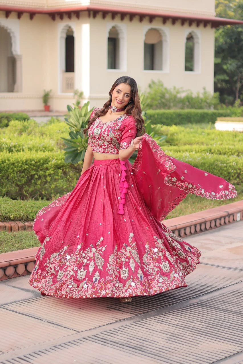 Woman in a pink traditional outfit with floral patterns standing outdoors.