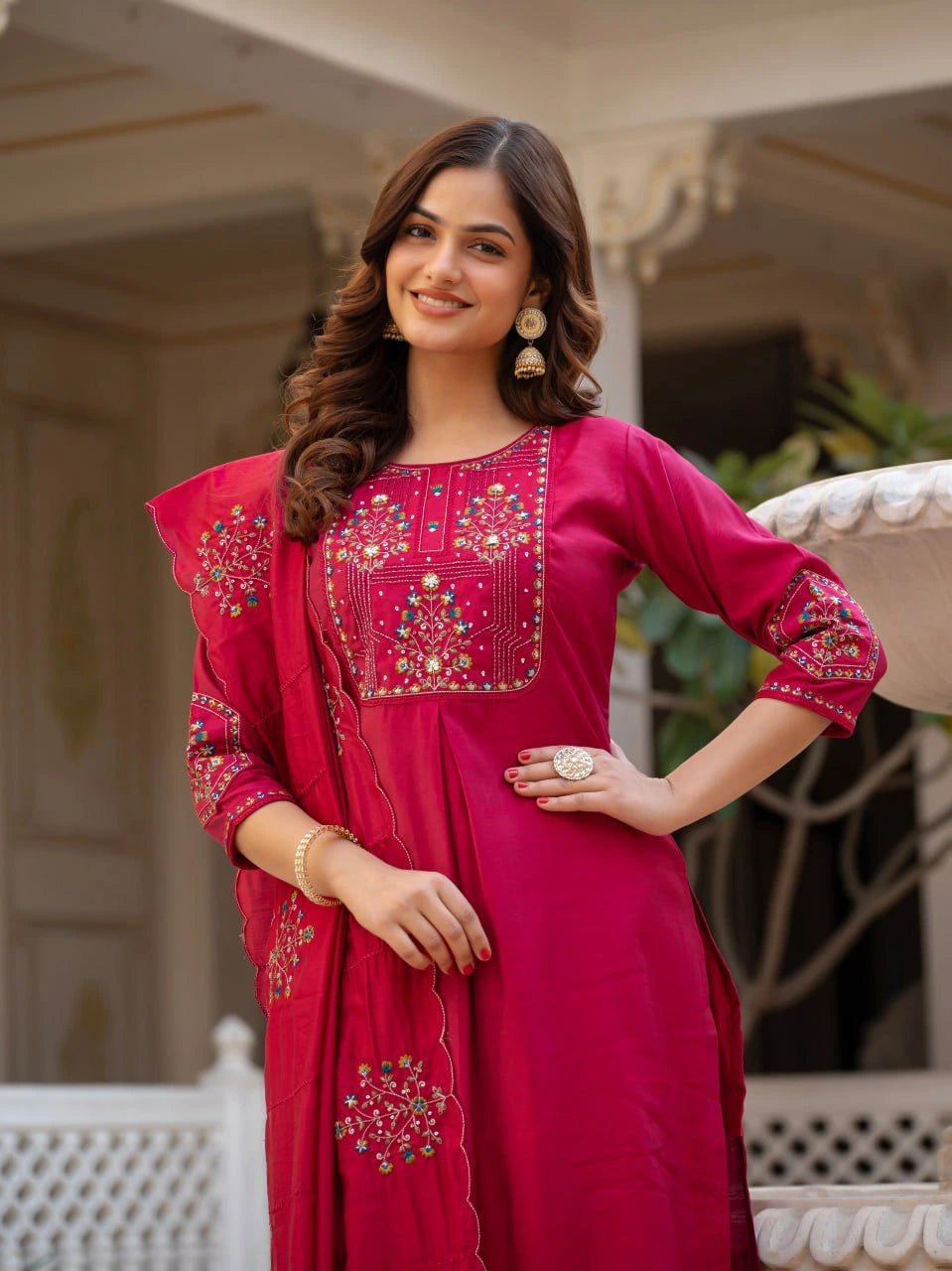 Woman wearing a pink traditional outfit with intricate designs, standing outdoors.