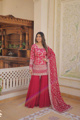 Woman in a red traditional outfit with floral patterns in an ornate room.
