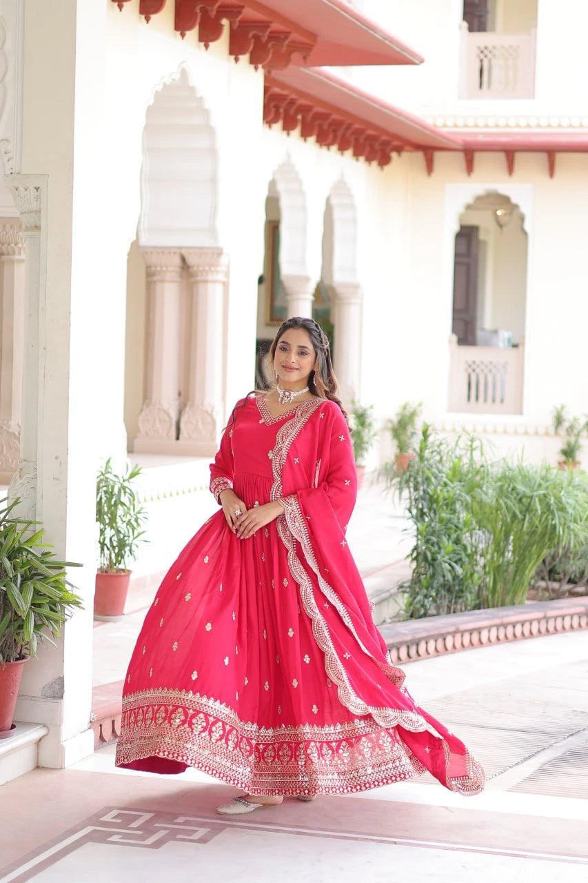 Woman in a red traditional outfit standing in front of a decorative building entrance.