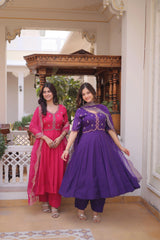 Two women in traditional outfits standing in a decorative indoor setting.