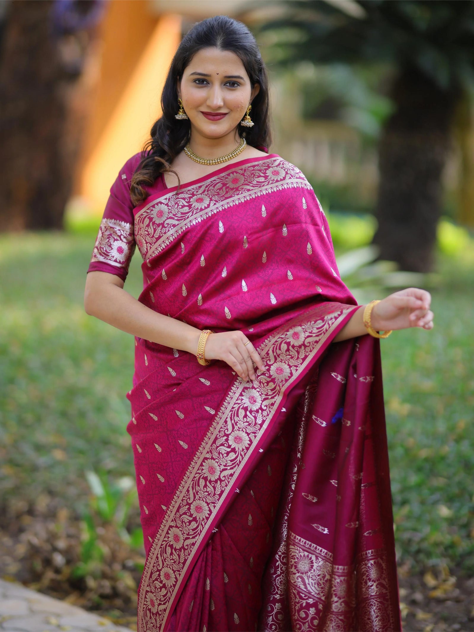 Woman wearing a pink saree with a blurred green background