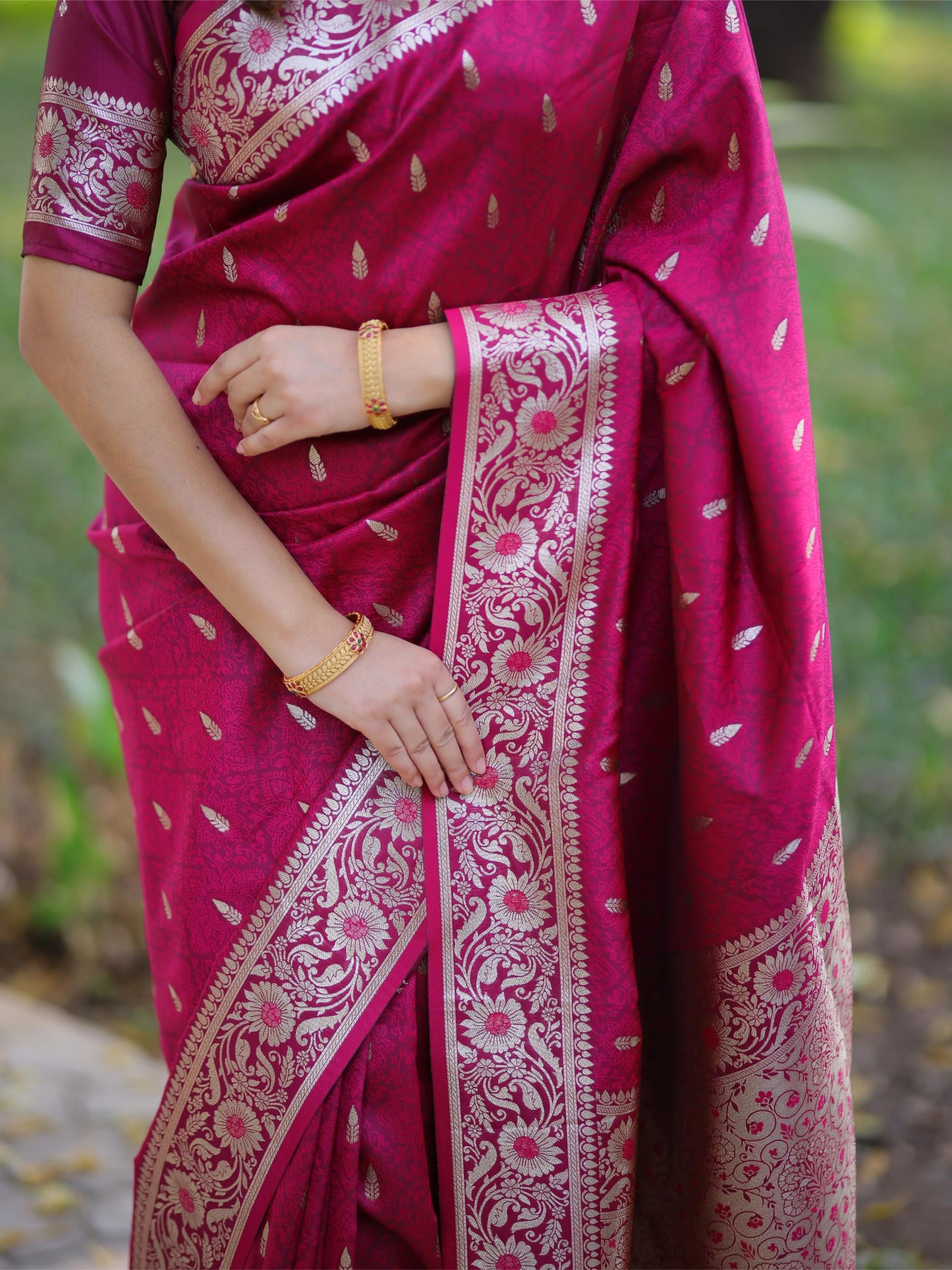 Person wearing a pink saree with white patterns, holding it with one hand.