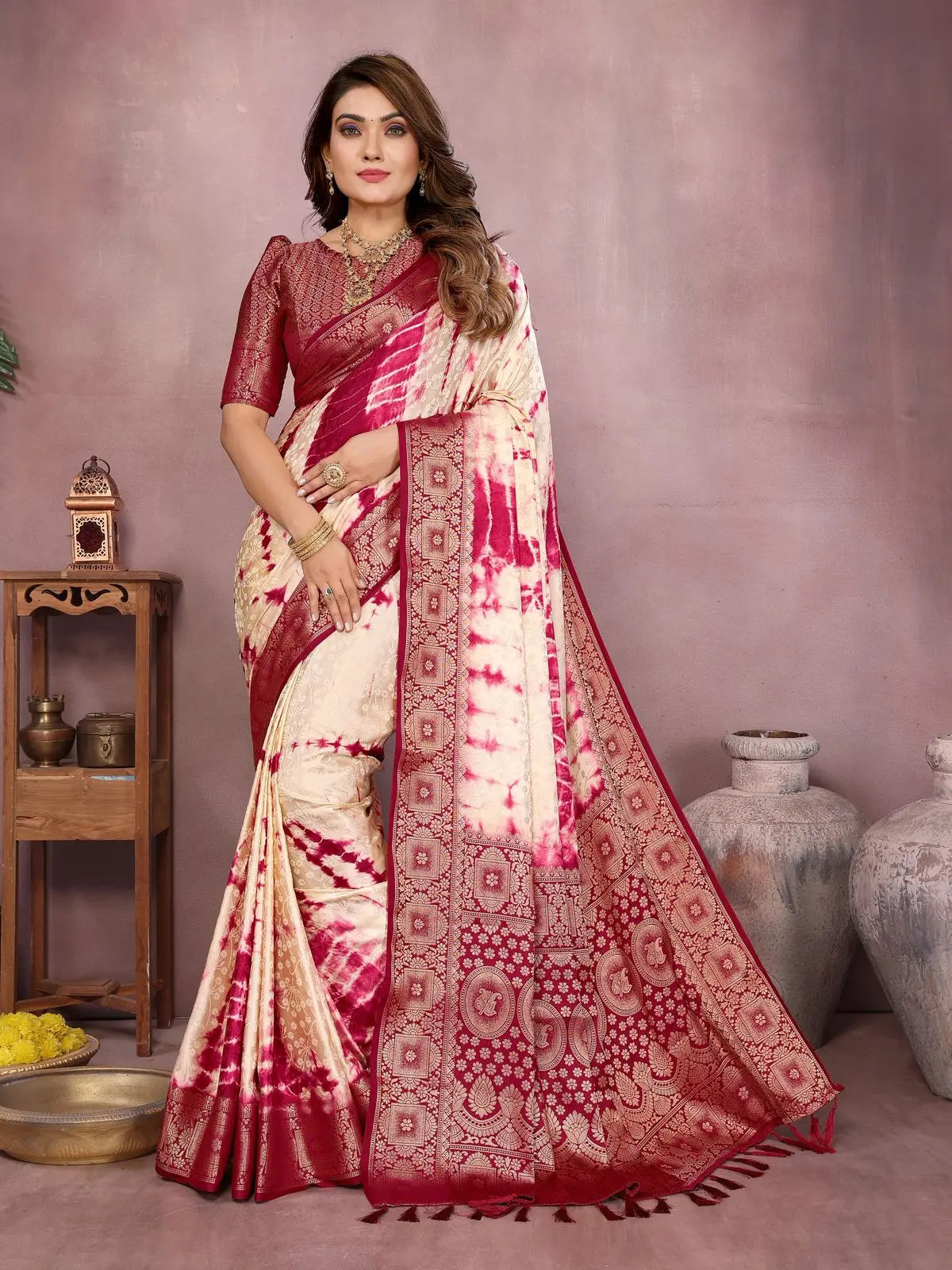 Woman wearing a red and white saree with intricate patterns in a decorative setting.