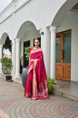 Woman in a pink saree standing in front of a white building with columns.