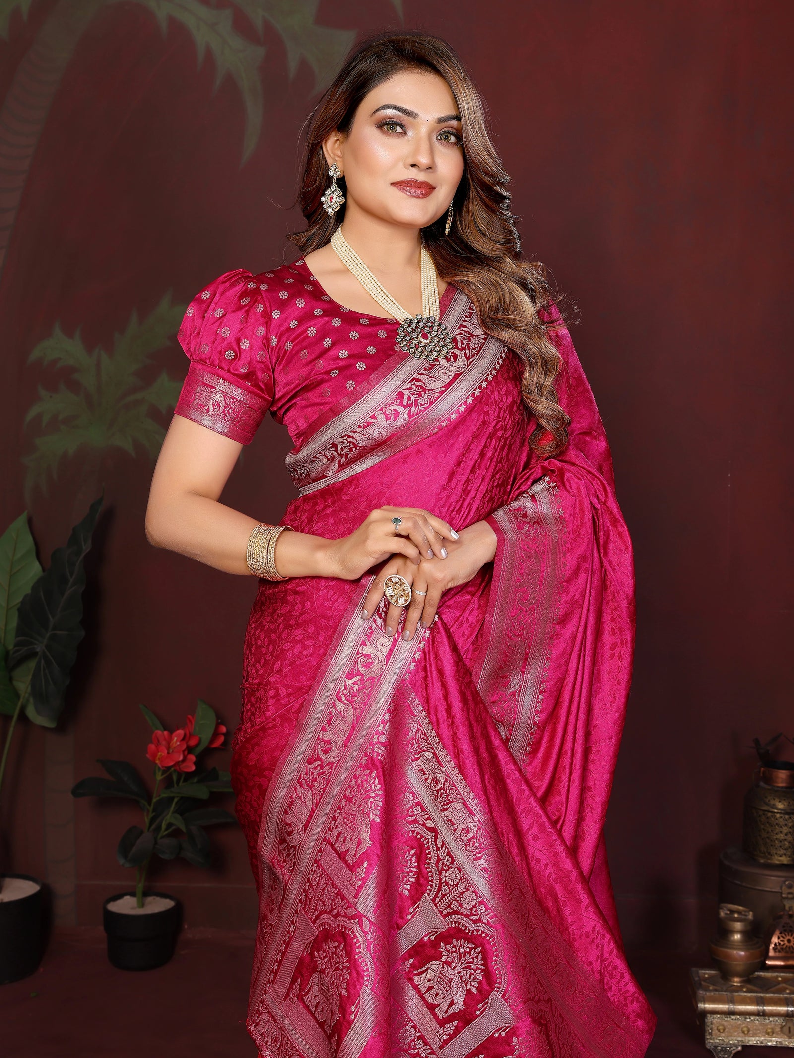 Woman in a pink saree with white patterns against a dark background