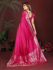 Woman wearing a bright pink saree with white embroidery against a dark background