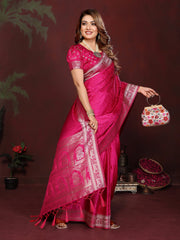 Woman in a pink saree holding a decorative bag against a dark background
