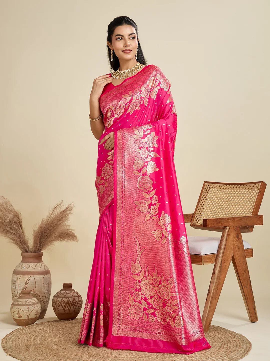 Woman wearing a pink saree with gold embroidery in a minimalistic setting.