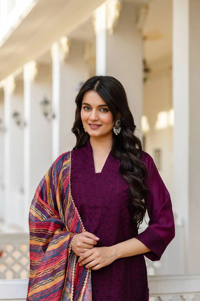 Woman in a purple outfit with a colorful shawl standing outdoors.