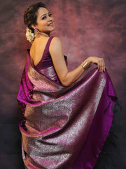 Woman wearing a purple saree with a patterned design against a dark background