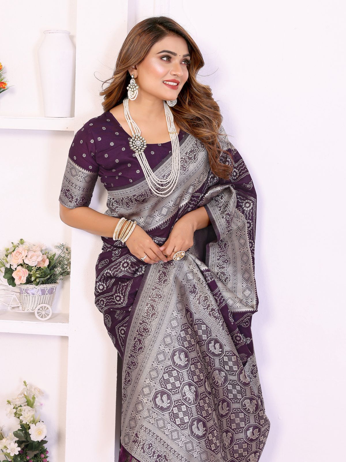 Woman wearing a purple and gray saree with jewelry against a white background