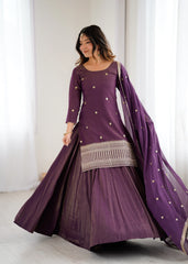 Woman wearing a purple traditional outfit with a matching dupatta in a bright room.
