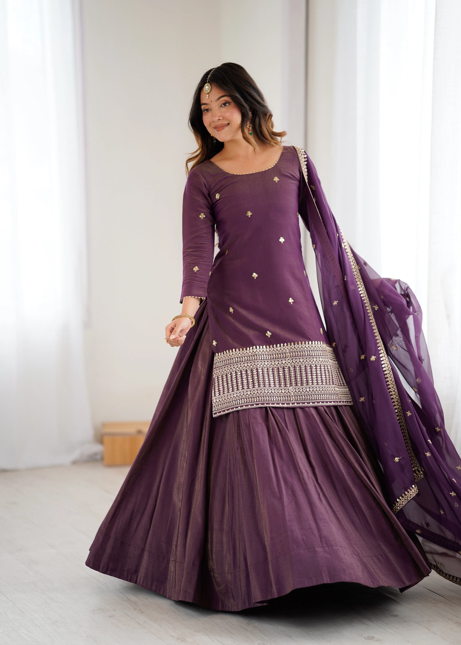 Woman wearing a purple traditional outfit with a matching shawl indoors.