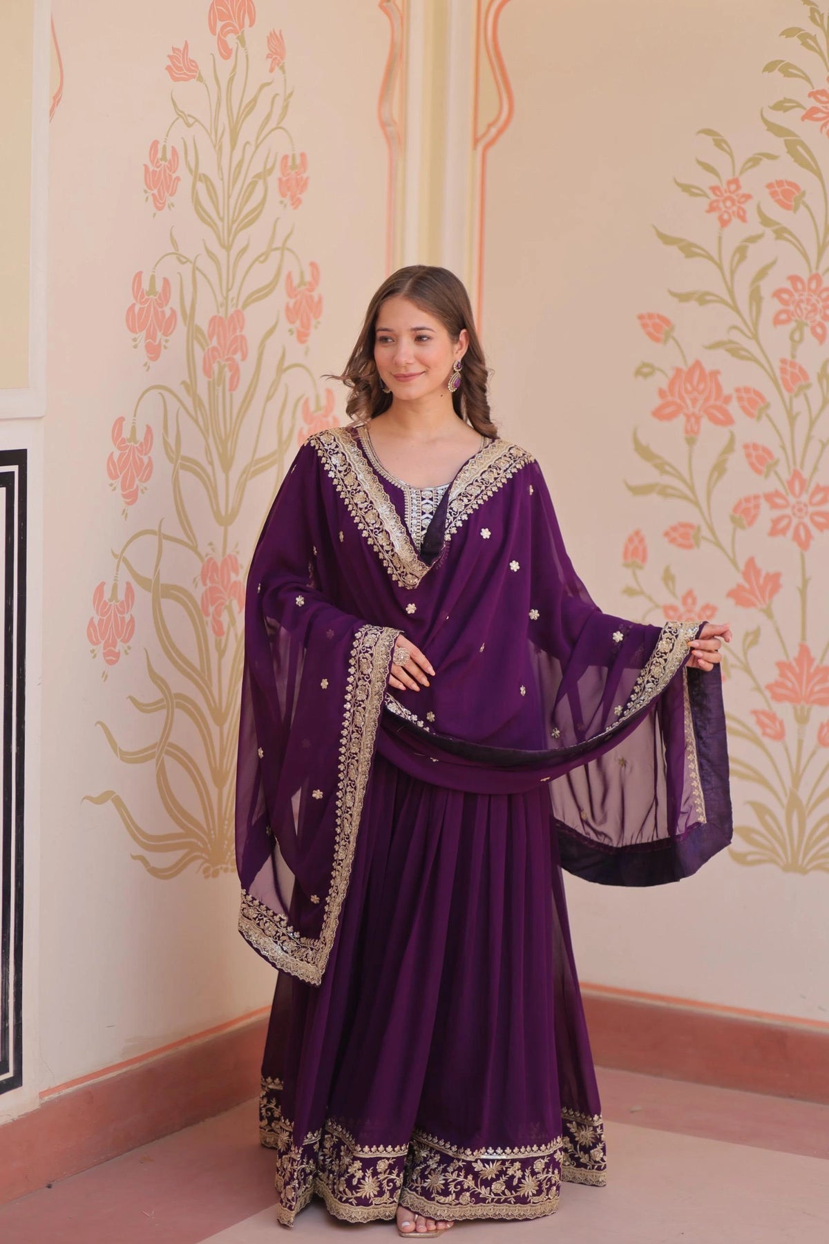 Woman in a purple traditional outfit with floral wall design