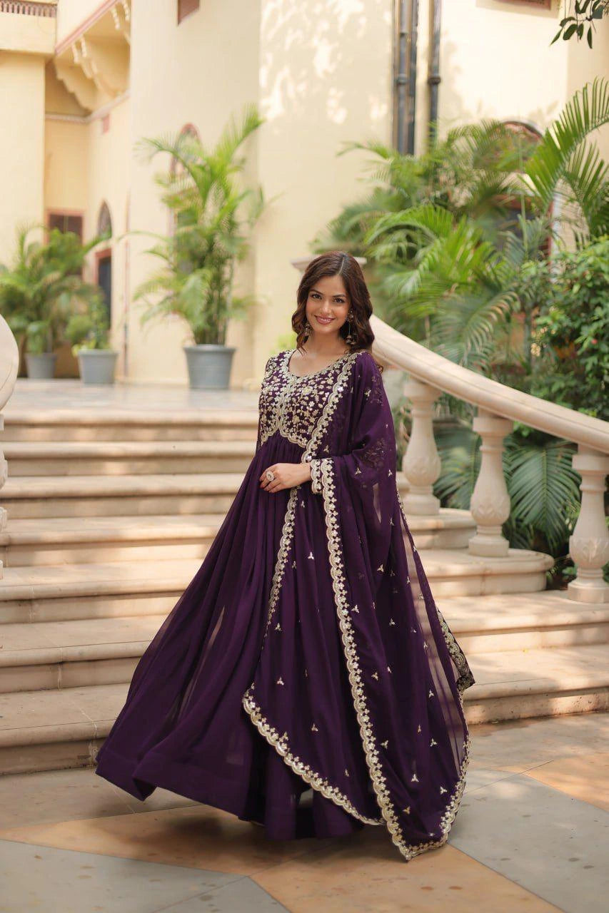 Woman in a purple traditional outfit standing on steps with greenery in the background