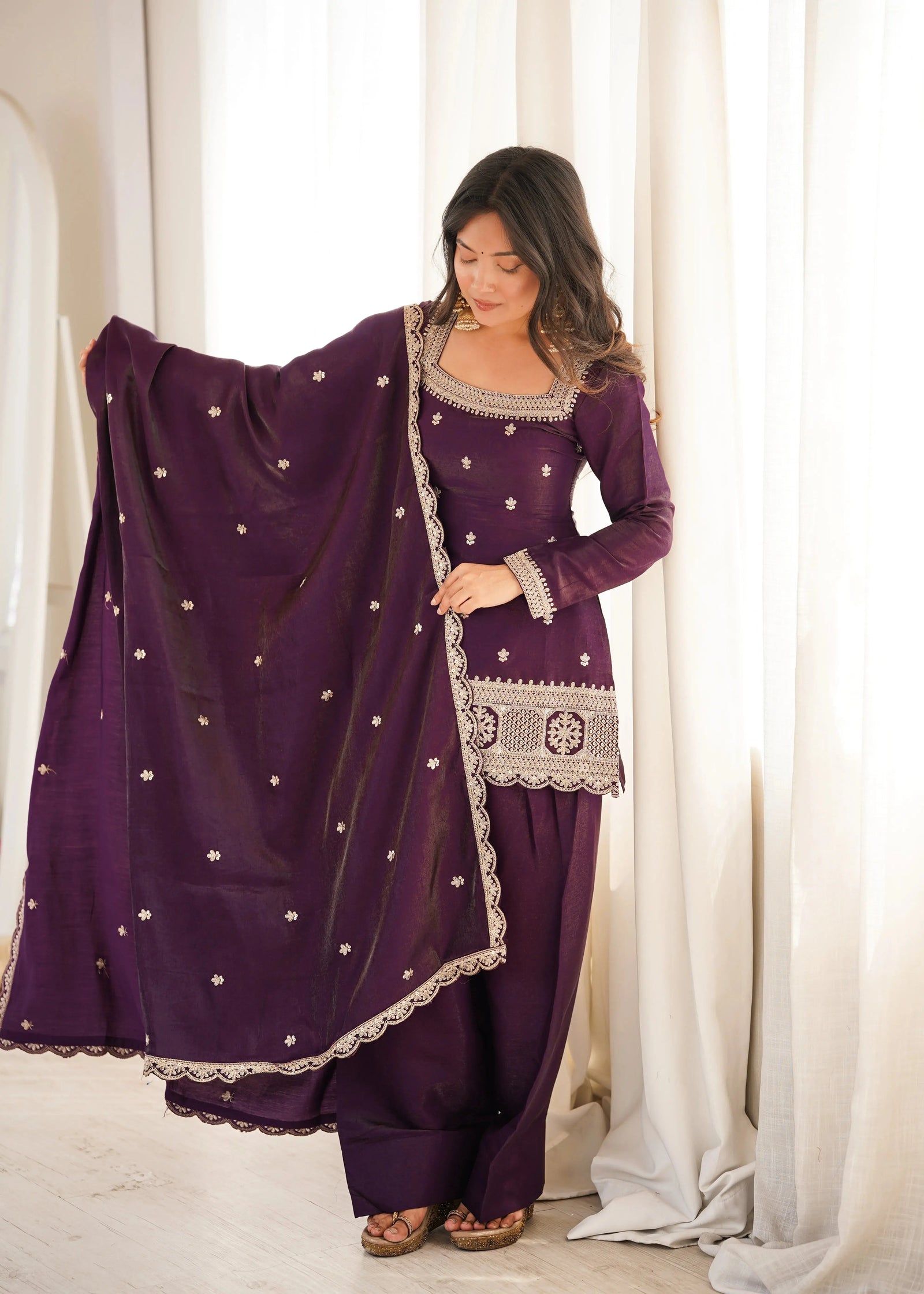 She gracefully drapes a matching sheer dupatta adorned with delicate embellishments.