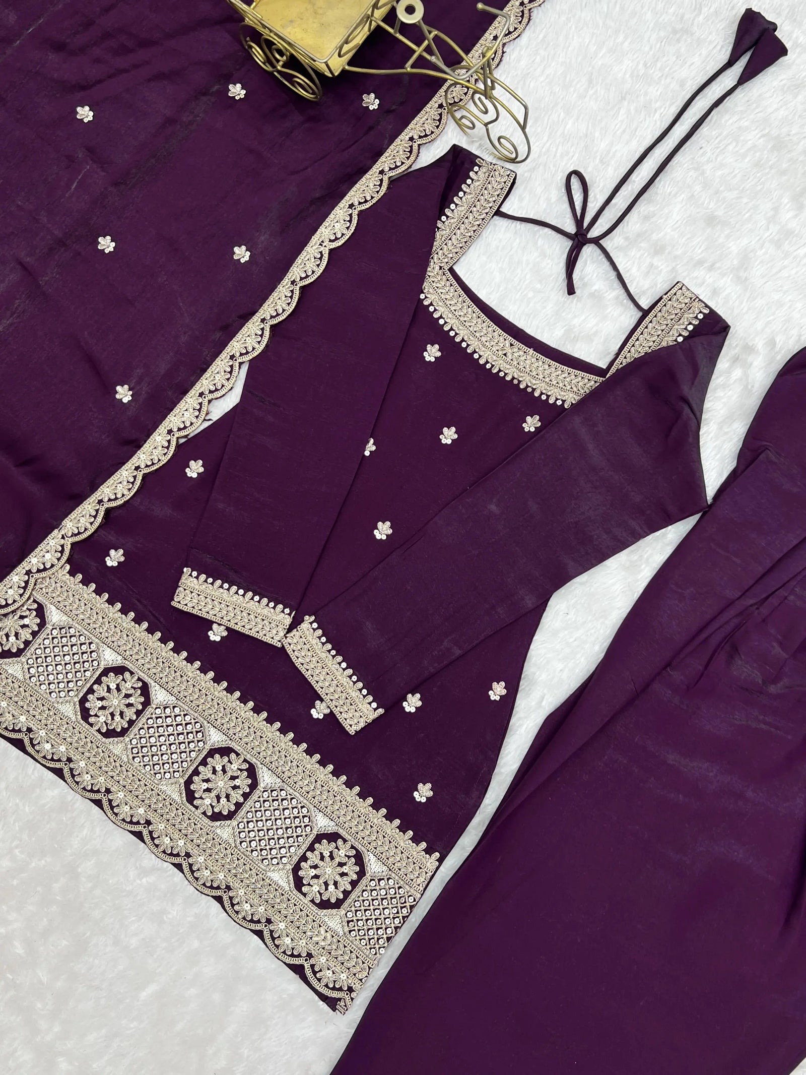 Purple traditional outfit with intricate white embroidery on a light background