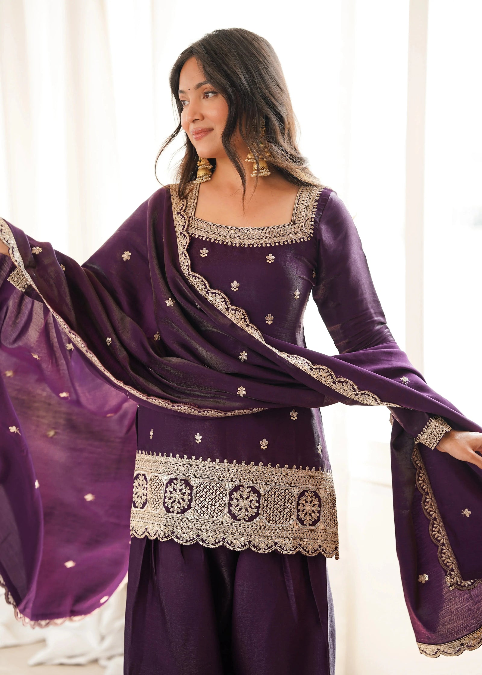 Woman wearing a purple traditional outfit with gold embroidery in a bright setting