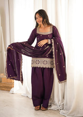 Woman in a traditional outfit with a purple dress and dupatta against a white curtain background