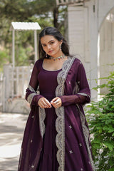 Woman wearing a purple traditional outfit with intricate designs outdoors.