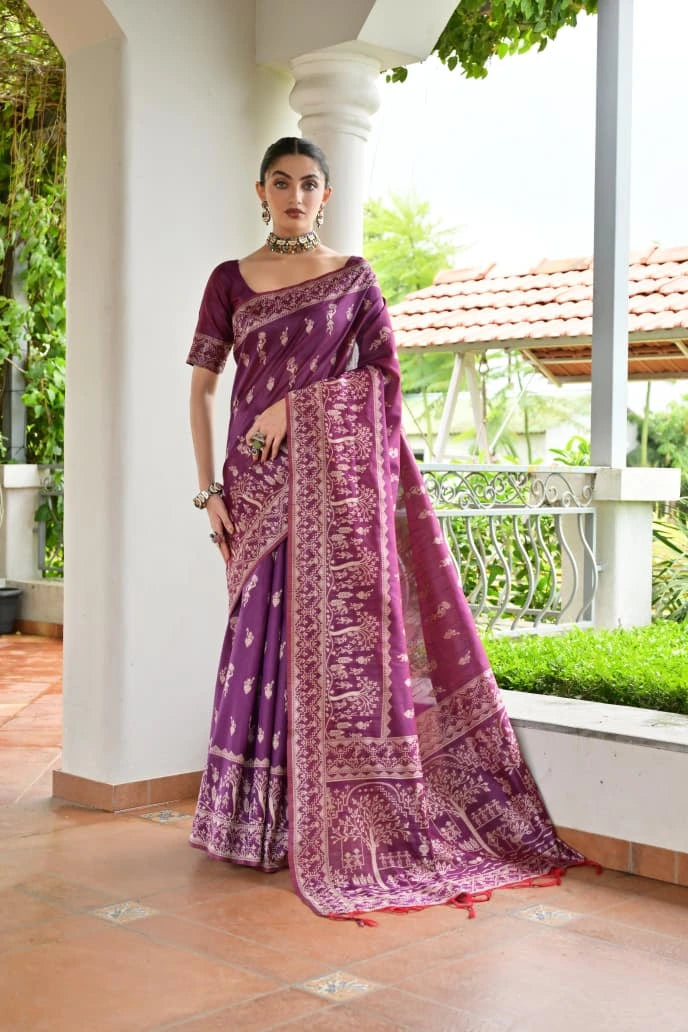 Woman wearing a purple saree with a white pattern, standing outdoors.