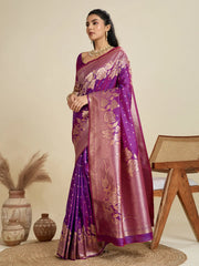 Woman wearing a purple saree with gold patterns in a minimalistic setting.