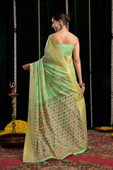Woman in a green saree with floral patterns on a dark background