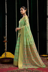 Woman in a green saree with a patterned design standing against a black background.