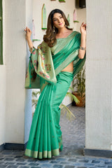 Woman in a green saree standing in a doorway.