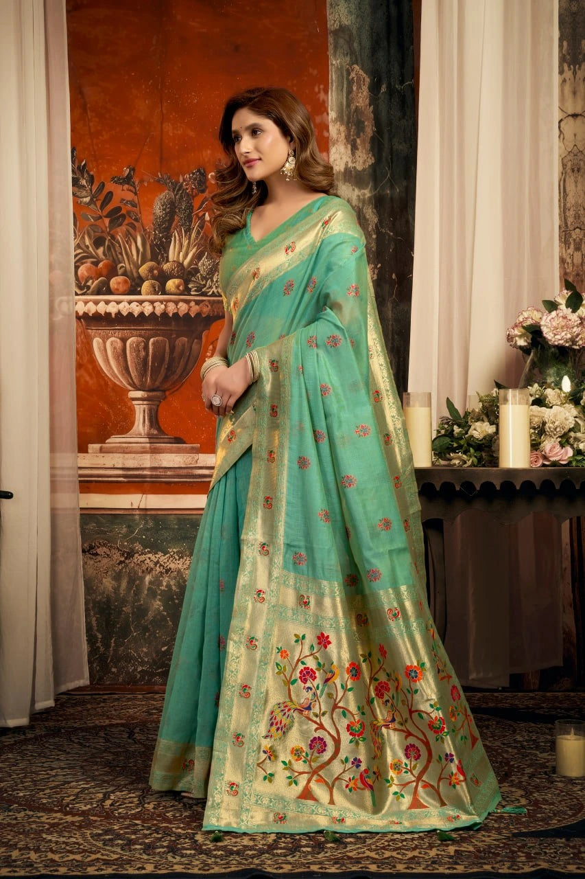Woman wearing a light blue saree with floral patterns in an indoor setting.