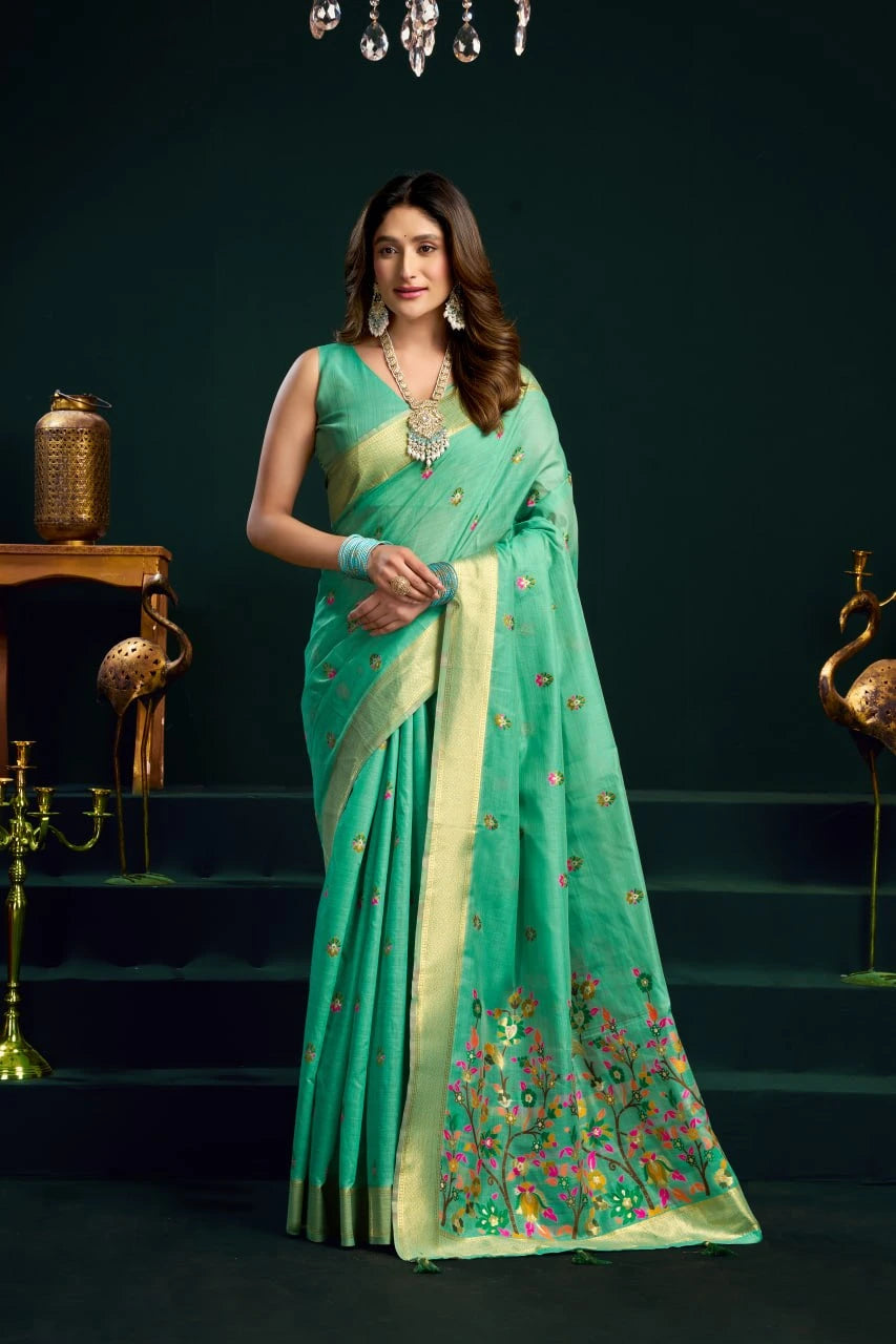 Woman wearing a green saree with floral patterns in an elegant indoor setting.