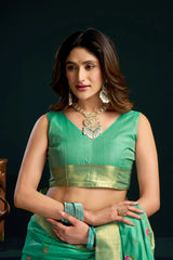 Woman wearing a green traditional outfit with jewelry against a dark background