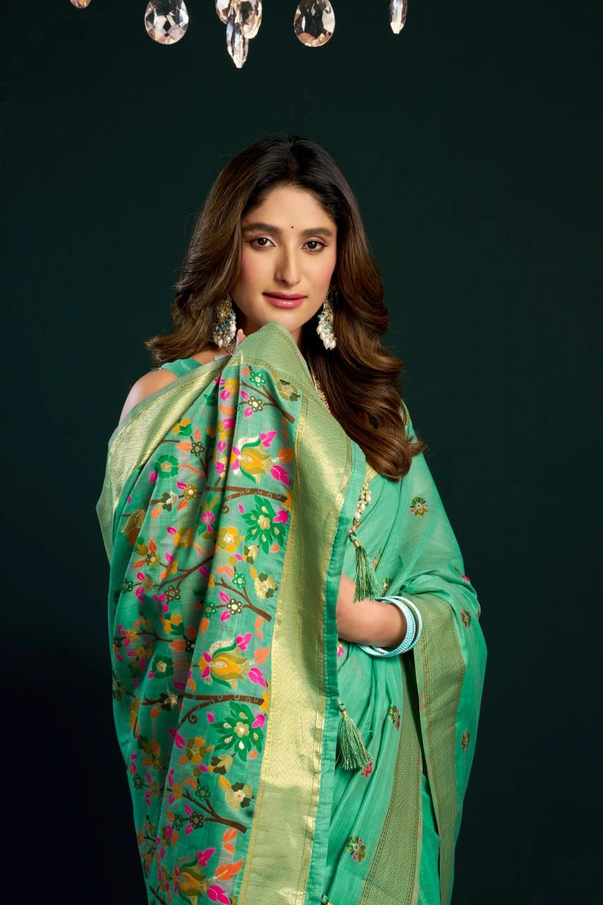 Woman wearing a green saree with floral patterns against a black background