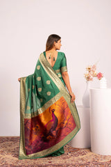 Woman wearing a green saree with a peacock design, standing against a white background.