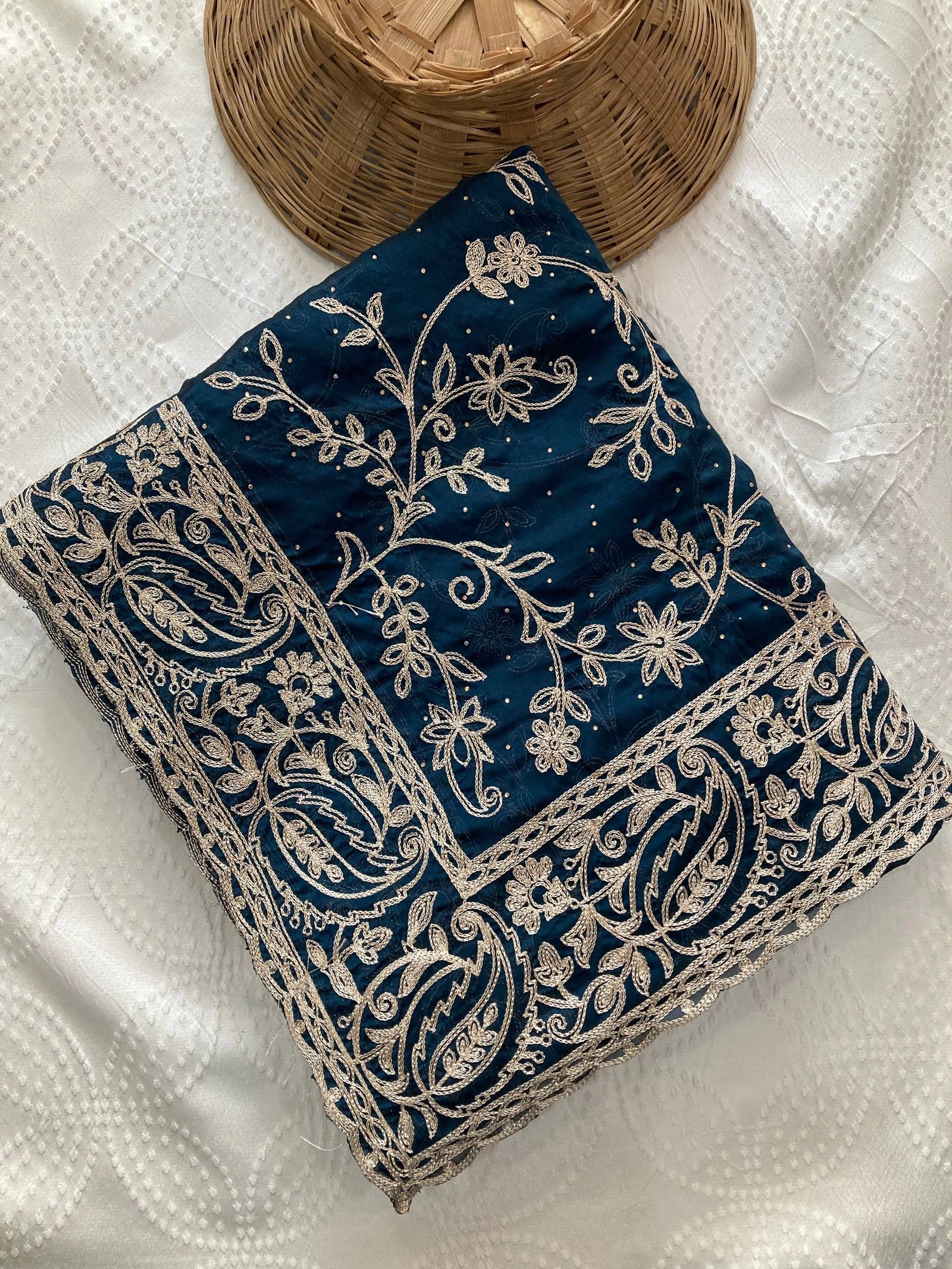 Navy blue fabric with intricate white embroidery on a textured white surface.