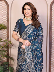 Woman wearing a blue saree with a floral pattern against a neutral background
