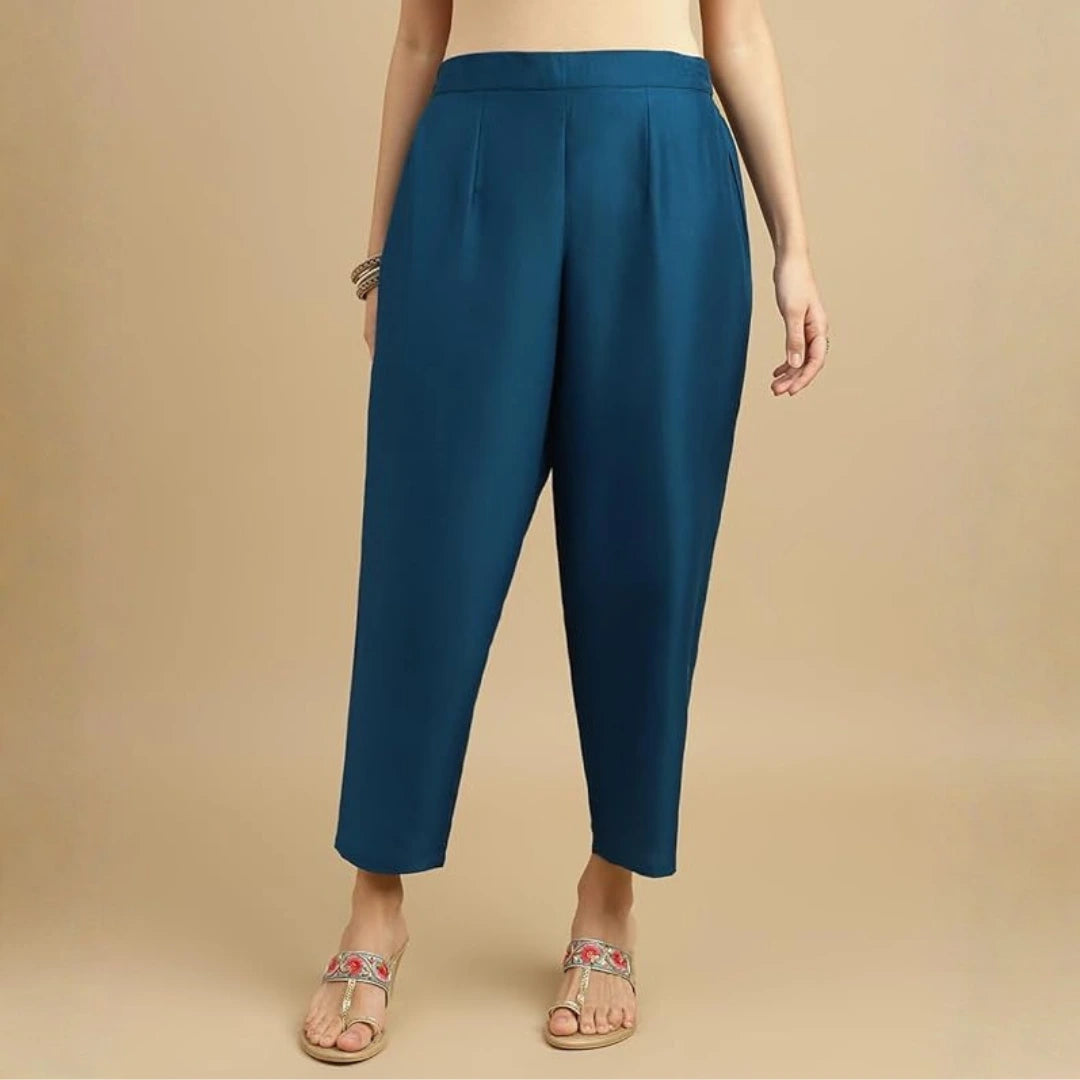 Teal pants worn by a person on a beige background