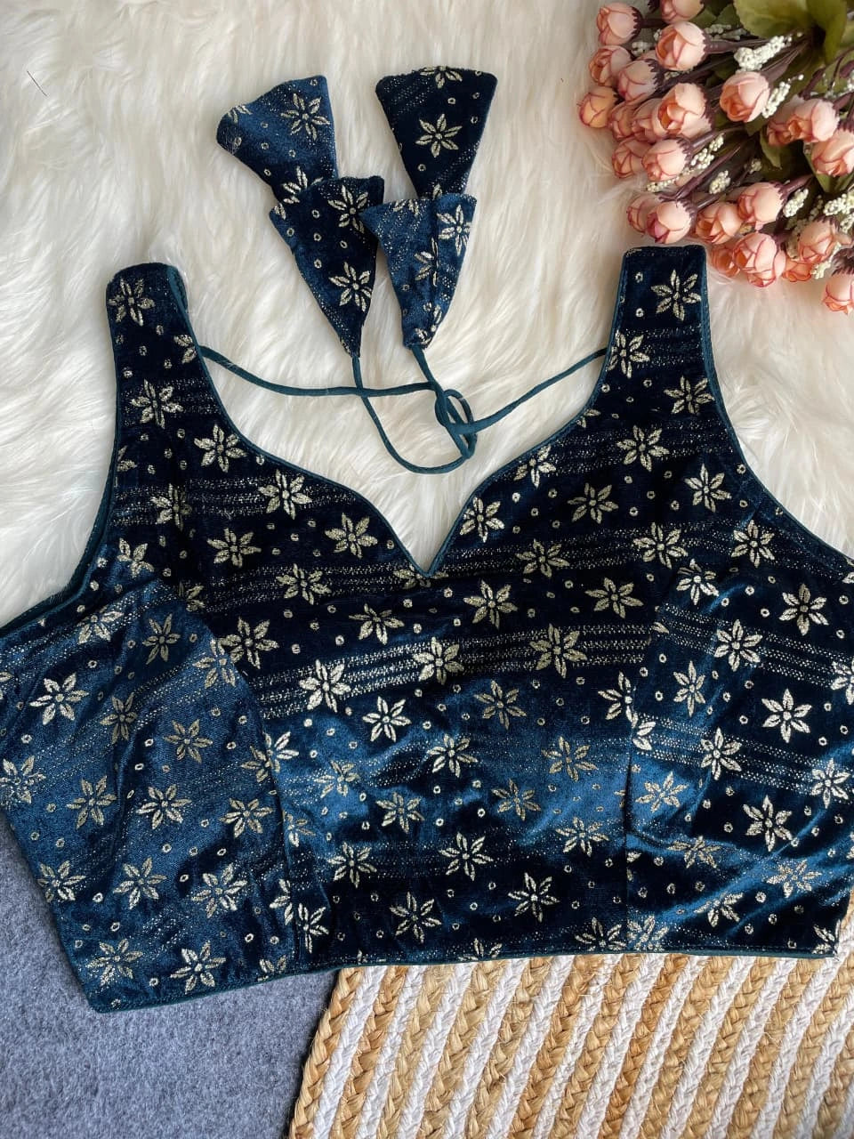 Blue floral-patterned top on a textured surface with flowers in the background