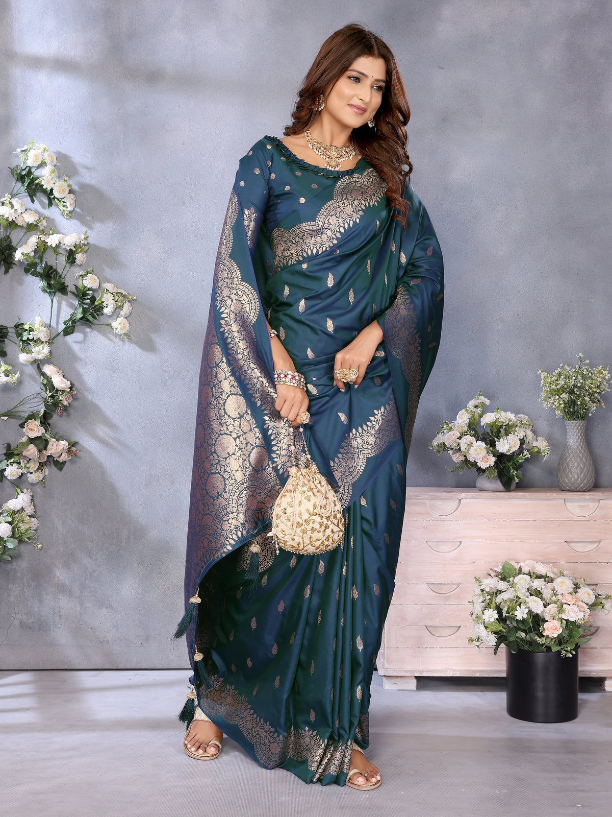 Woman in a blue saree with silver patterns standing in a decorated room.
