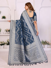 Woman wearing a blue saree with a white pattern in a bright room.
