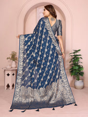 Woman wearing a blue saree with a white pattern in a decorated room.