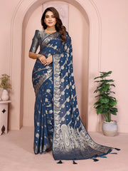 Woman wearing a blue saree with silver patterns in an indoor setting.
