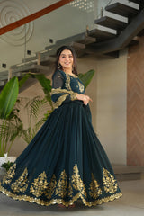Woman in a dark blue traditional outfit with gold embroidery standing indoors.