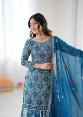 Woman wearing a blue and white patterned traditional outfit with a matching dupatta.