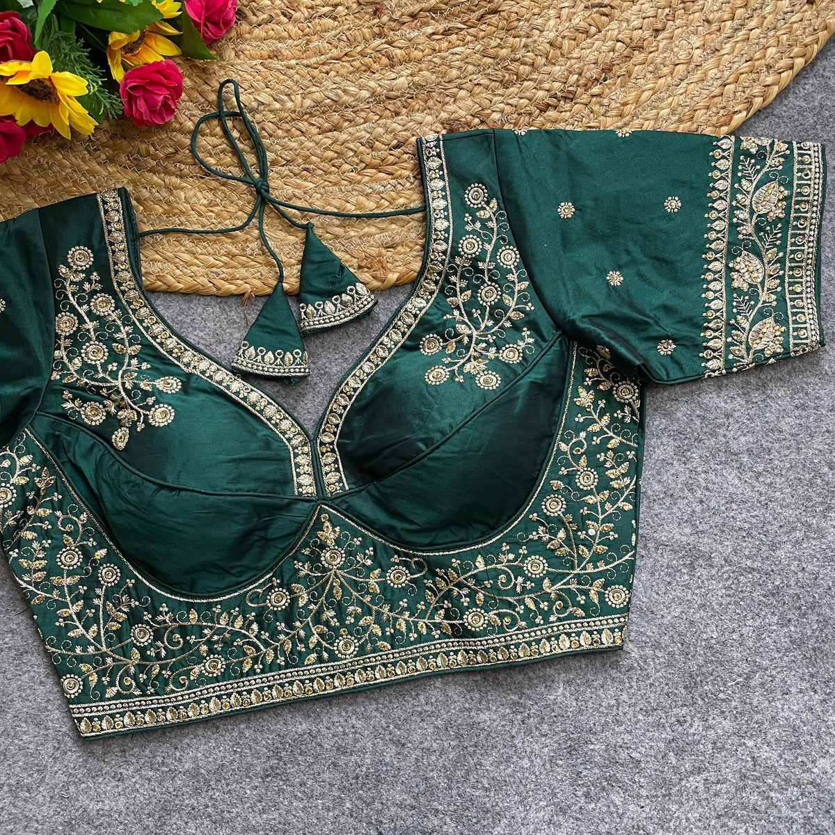 Green embroidered blouse on a textured surface with flowers in the background